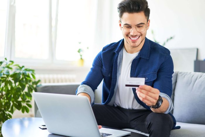 Cheerful,Young,Man,Using,Credit,Card,And,Laptop,To,Pay